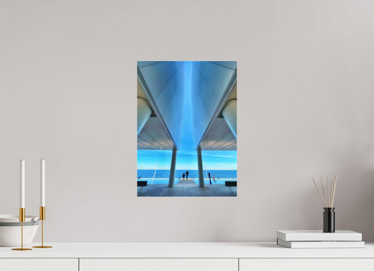 Framed acrylic-glass wall print of blue seaside structure seen between columns