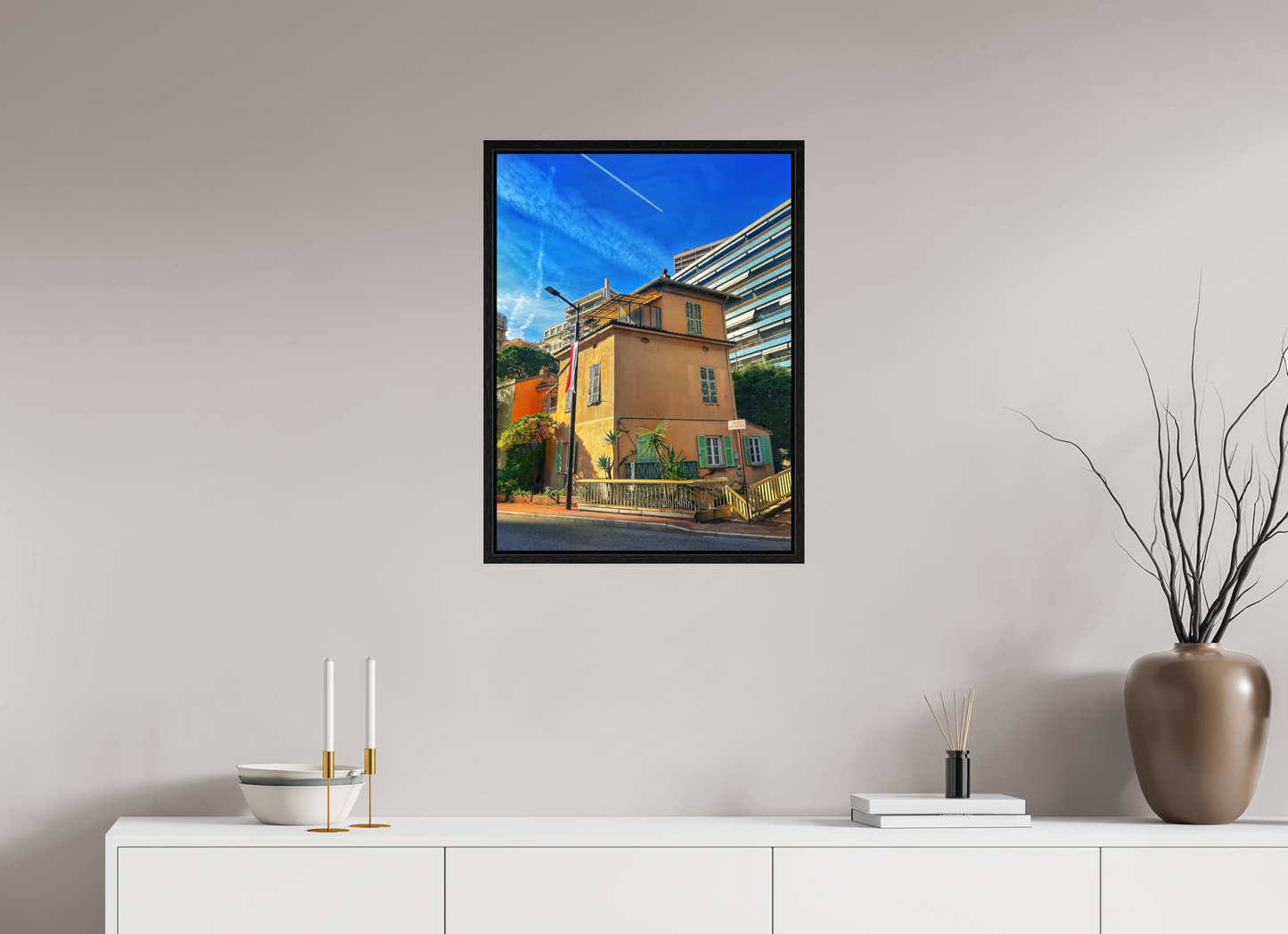 Framed street scene photo print in black floater frame, featuring a yellow building with window balconies.
