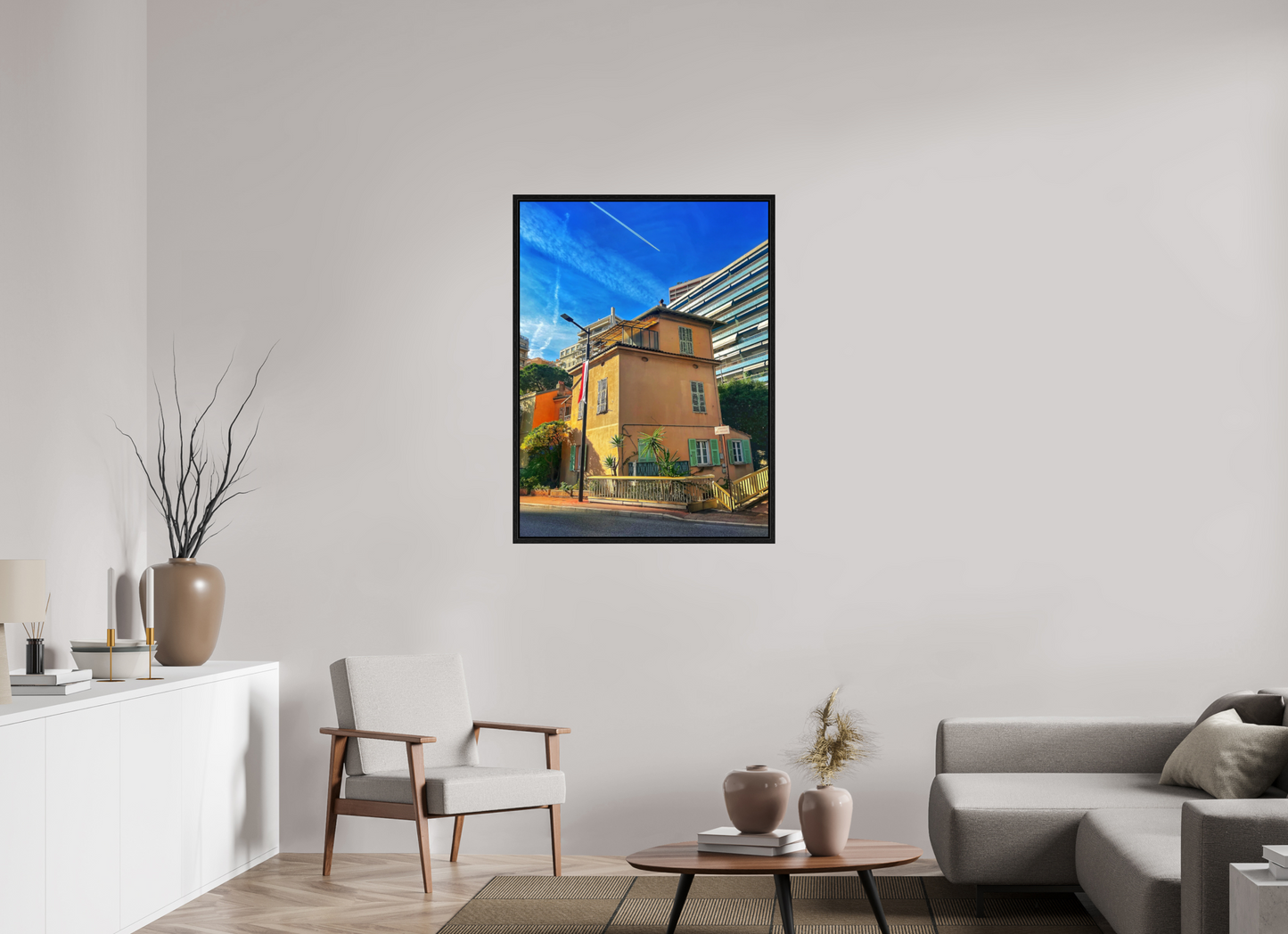 Framed street scene photo print in black floater frame, showing a yellow building and slanted rooflines.