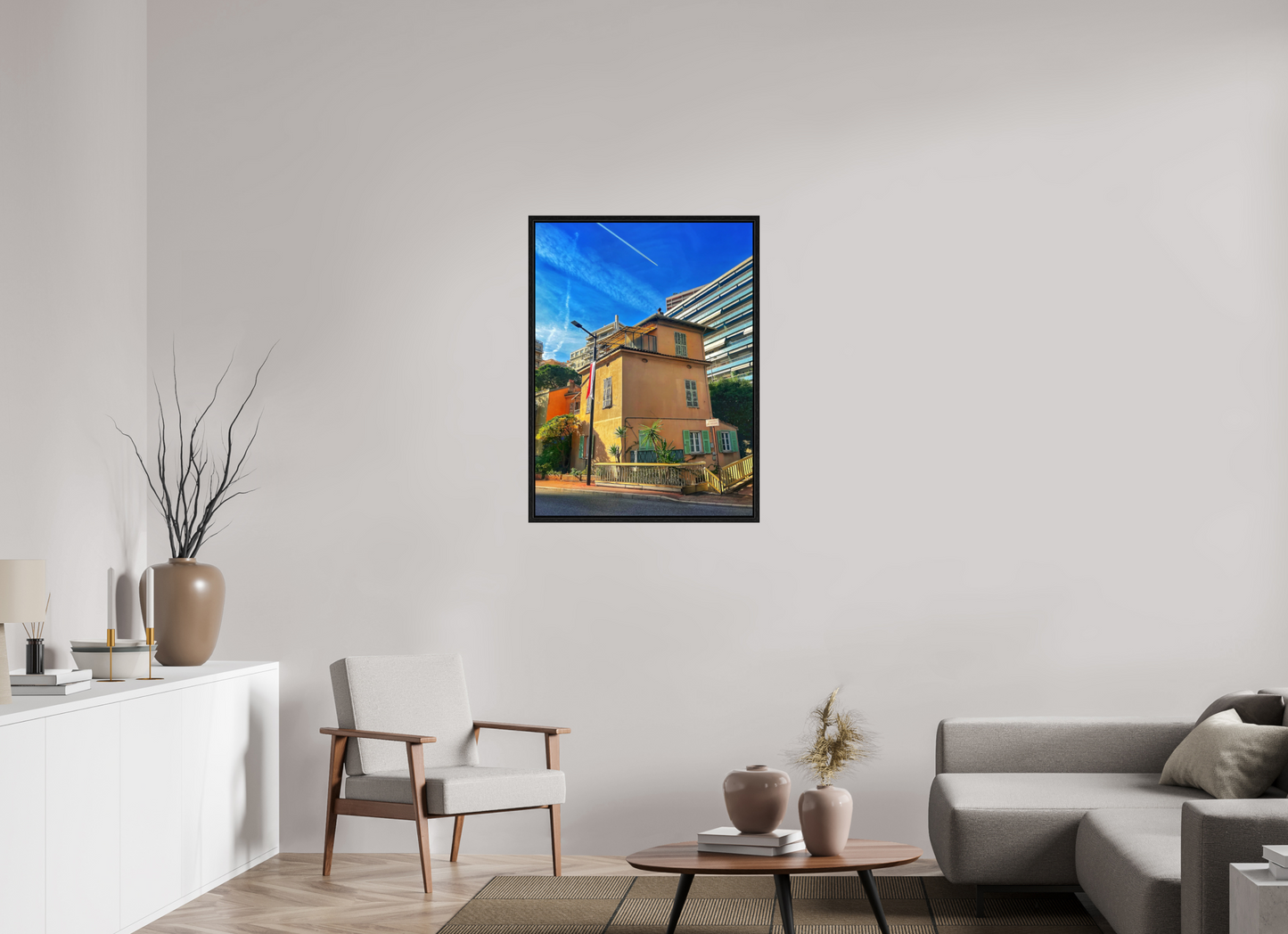 Framed street scene photo print in black floater frame, with a yellow house and blue daytime sky.