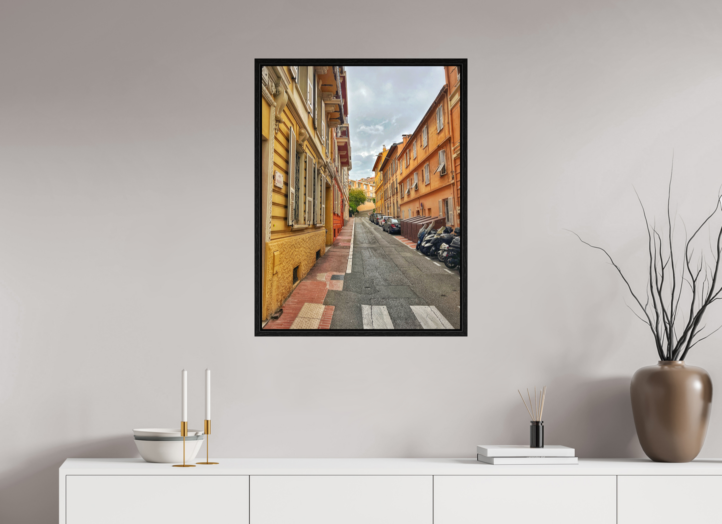 Square framed photo print of a European street corridor with yellow and orange buildings lining both sides