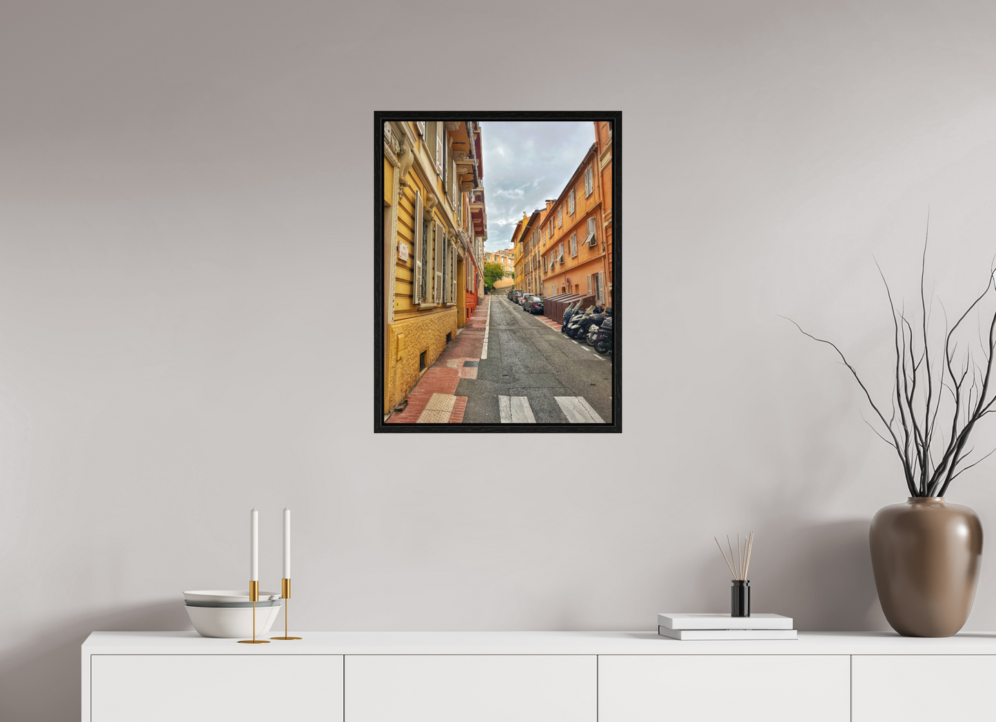 Square framed photo print showing a long view down a narrow street with parked cars on the right
